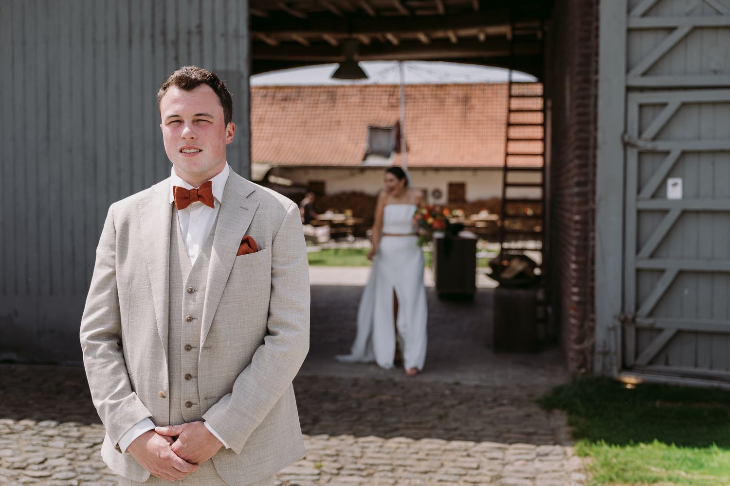 Elegantly dressed women in colorful gowns gather in a brick courtyard during an outdoor wedding celebration.