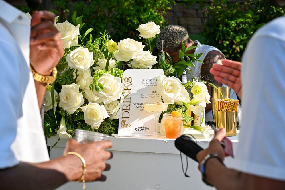 Elegant drinks station with white roses bouquet and cocktails at an outdoor social event.