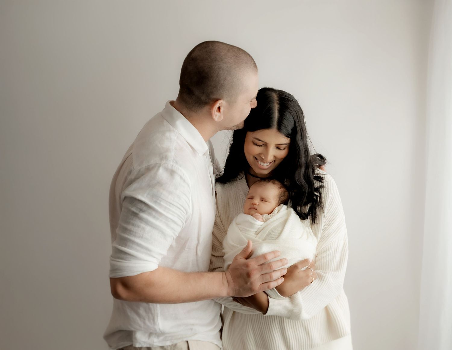 Parents cuddling newborn baby during photography session
