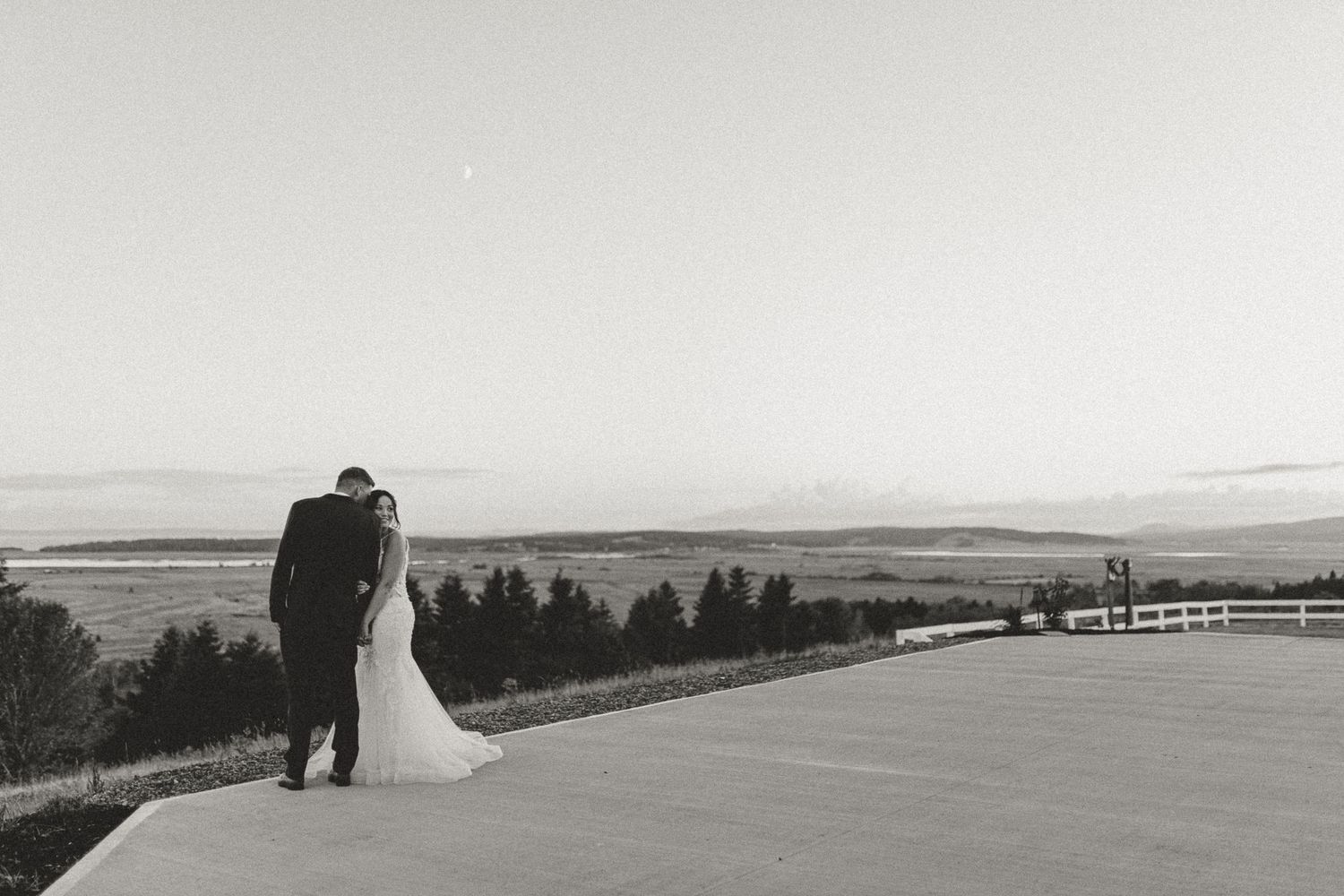 Romantic wedding couple sharing an intimate moment under a bridal veil, groom with beard and bride with pearl earrings.