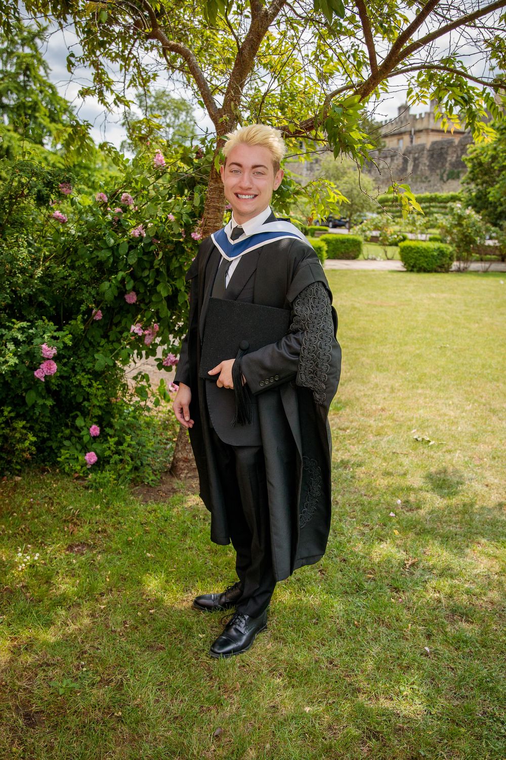 Graduation portraits taken outdoors with green trees and grass in the background.