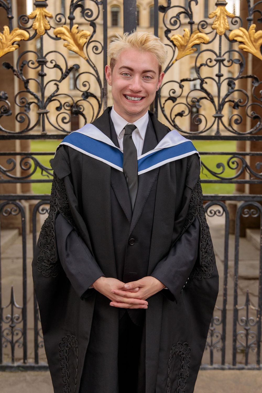 Academic graduation portraits taken in front of decorative metal gates and stone architecture.