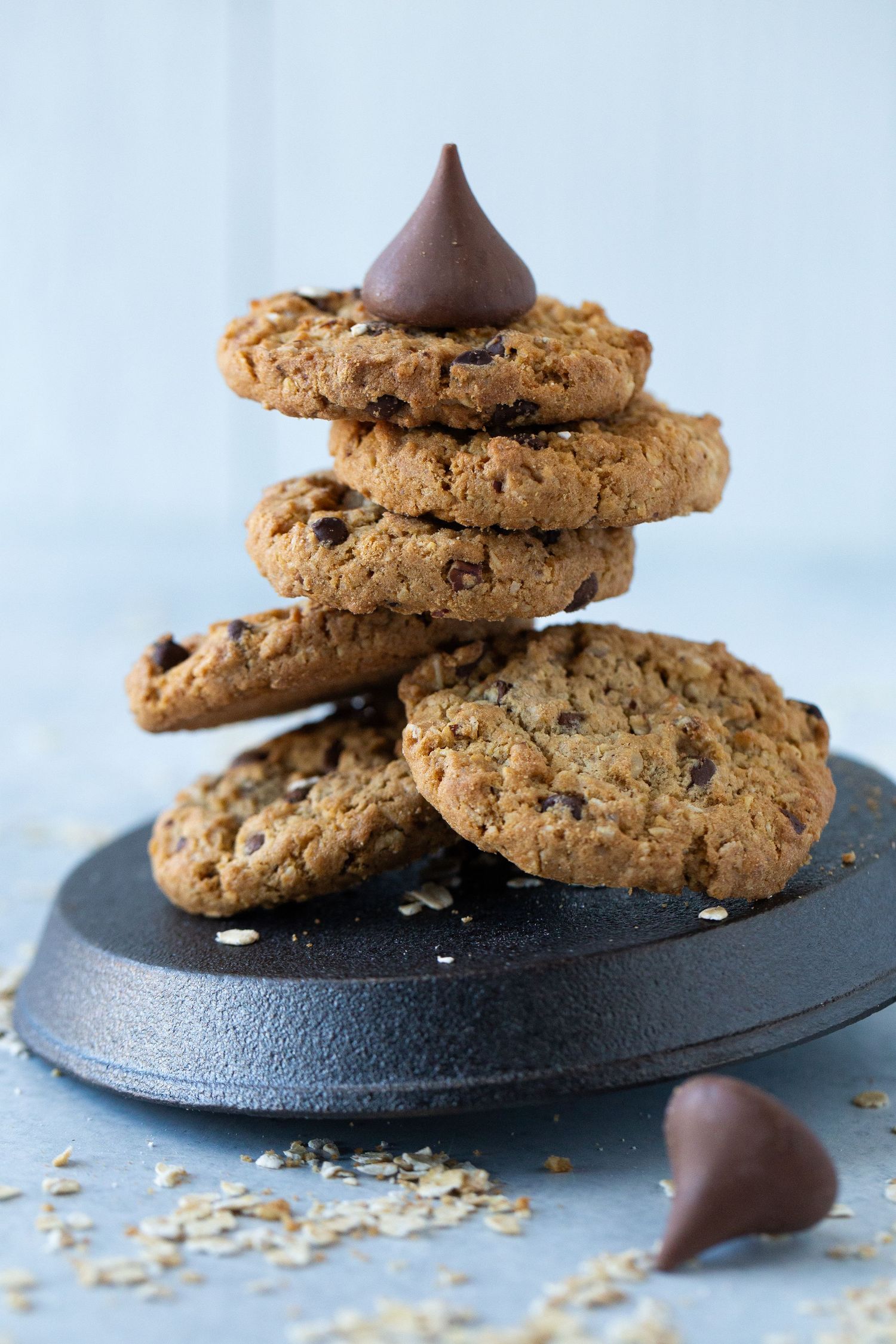 Photo of six Cowboy Cookies by HEB stacked haphazardly on top of a cast iron skillet and topped with a Hershey's chocolate kiss