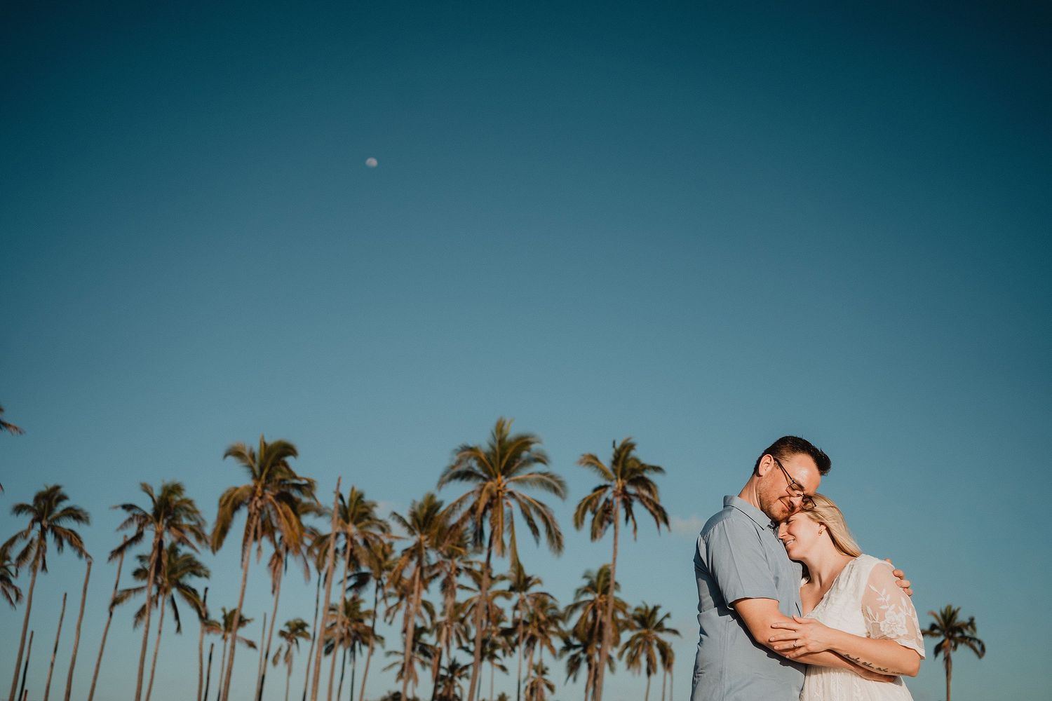 Pareja abrazándose entre palmeras durante sesión de fotos en Mazatlán con estilo natural y documental.
