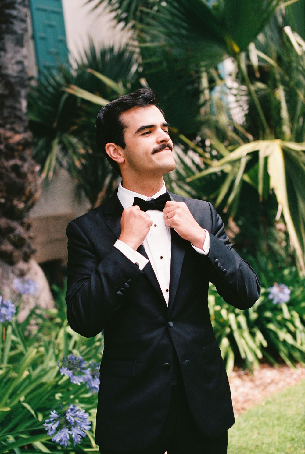 A groom fixes his bowtie before his wedding ceremony at the Santa Barbara Courthouse. Shot on 35mm film.