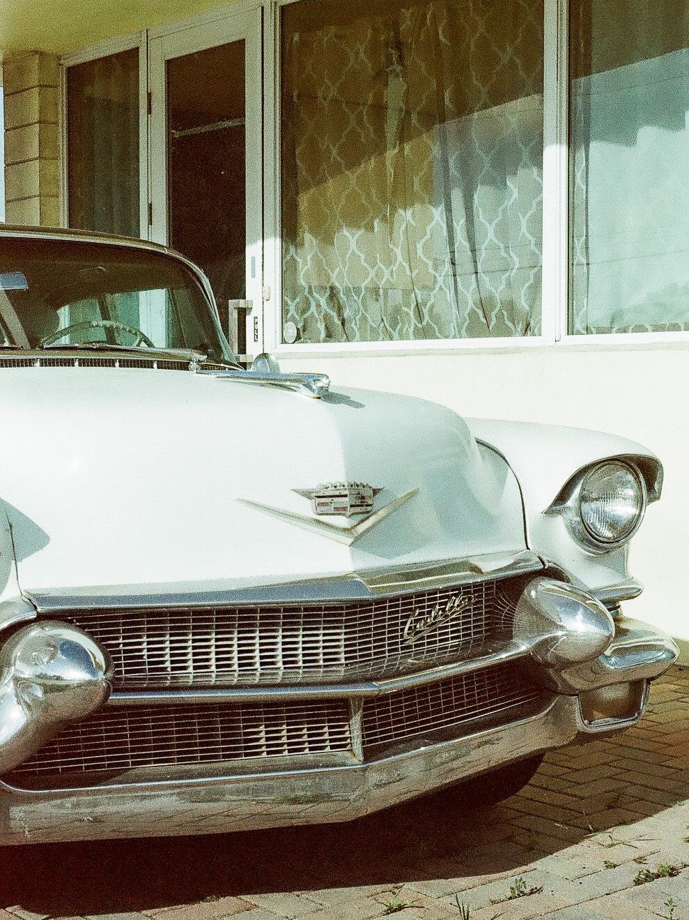 Vintage white Cadillac classic car parked in front of a building with decorative windows.