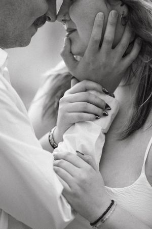 Natural light couples photography capturing a young couple kissing with whimsical styling in black and white with grain.