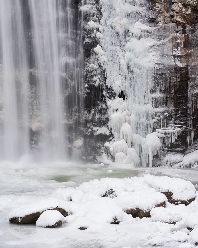 Frozen waterfall with icicles and snow-covered rocks in a winter landscape.