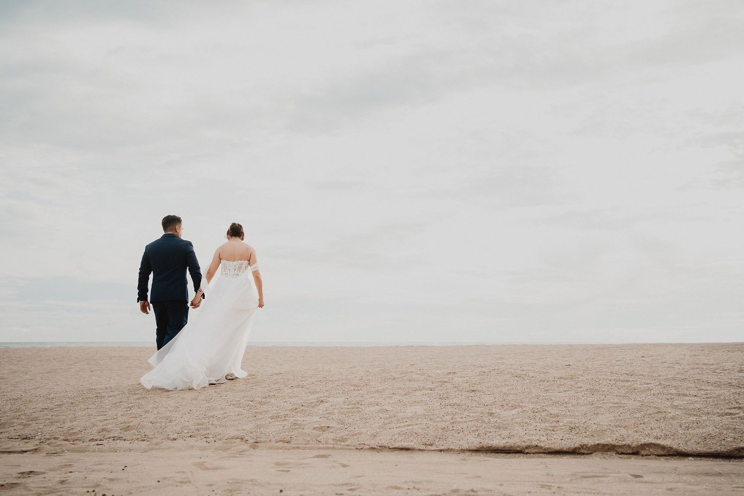 Novios caminando tomados de la mano sobre la playa durante una boda en Mazatlán