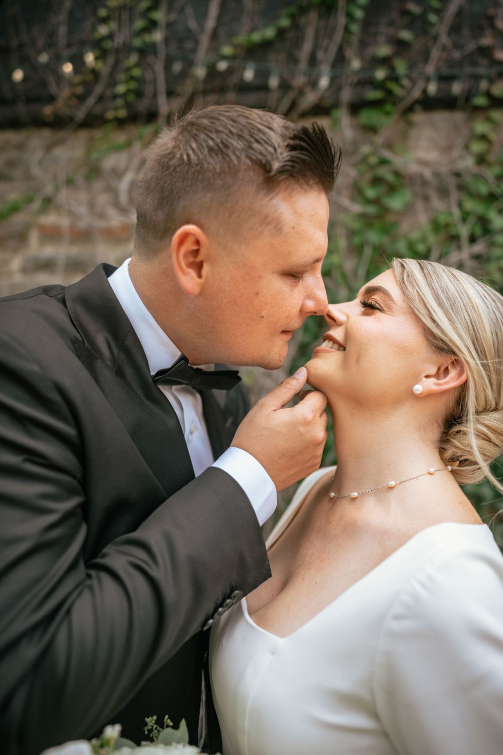 Groom tenderly touches bride's chin as they share an intimate moment during their wedding day.