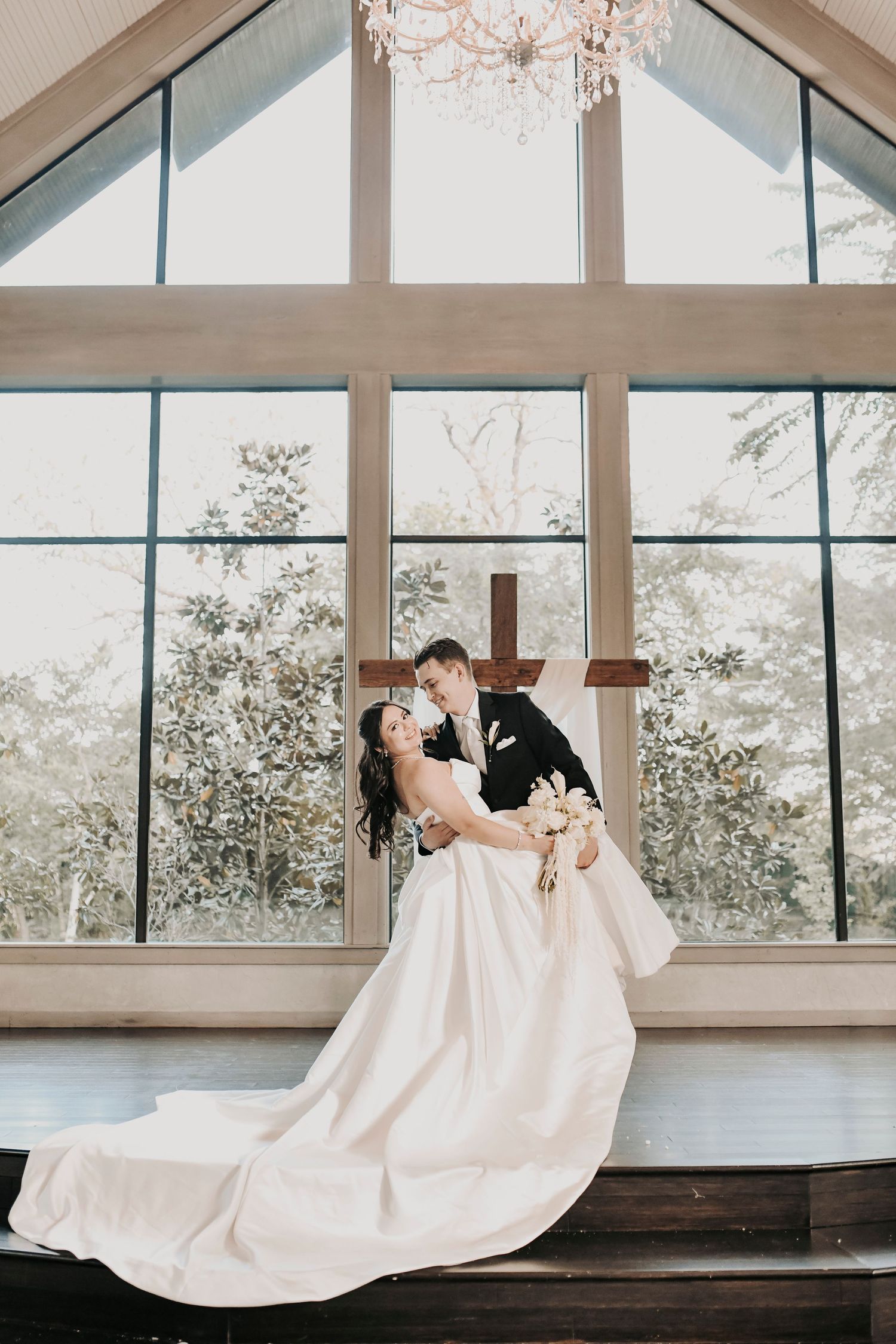 Newlyweds embracing inside Brighton Abbey's white chapel
