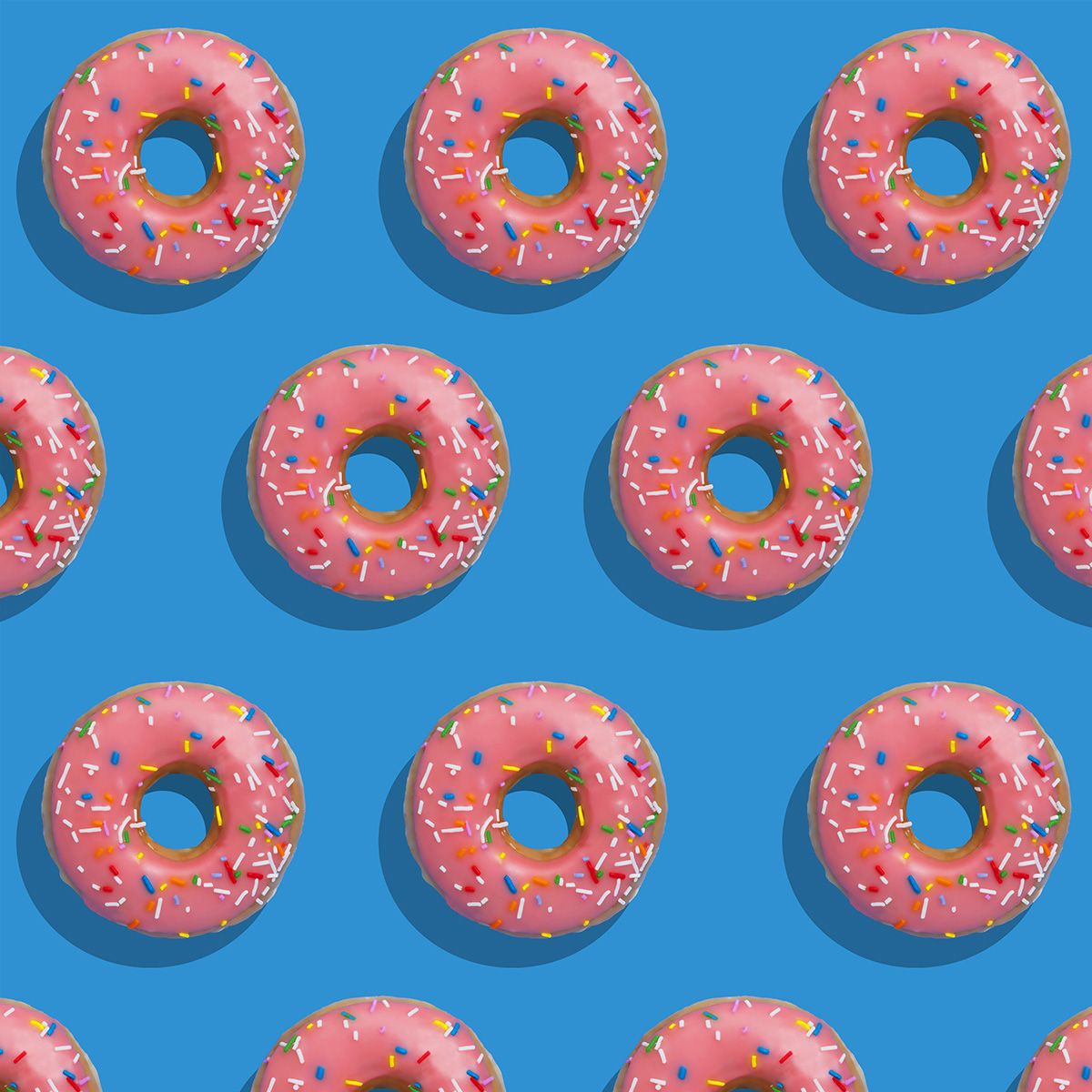 A seamless pattern of pink frosted donuts with colorful sprinkles arranged in rows on a bright blue background.