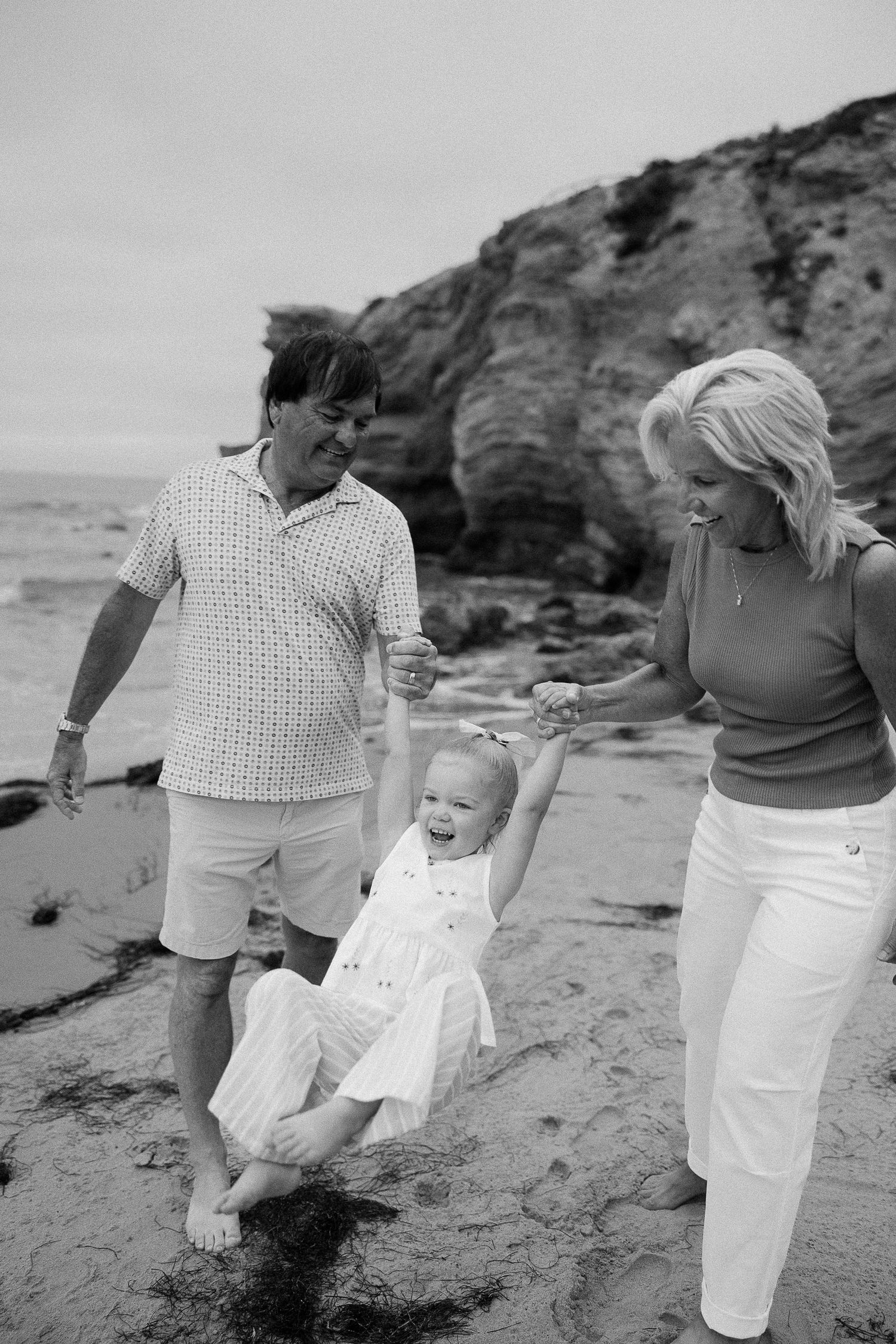 Toddler and grandparents smiling during Crystal Cove beach family photos