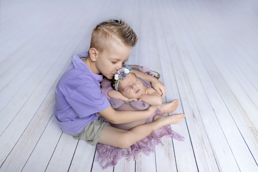 A dancer in purple performs graceful movements across a white wooden floor in a flowing sequence of poses.