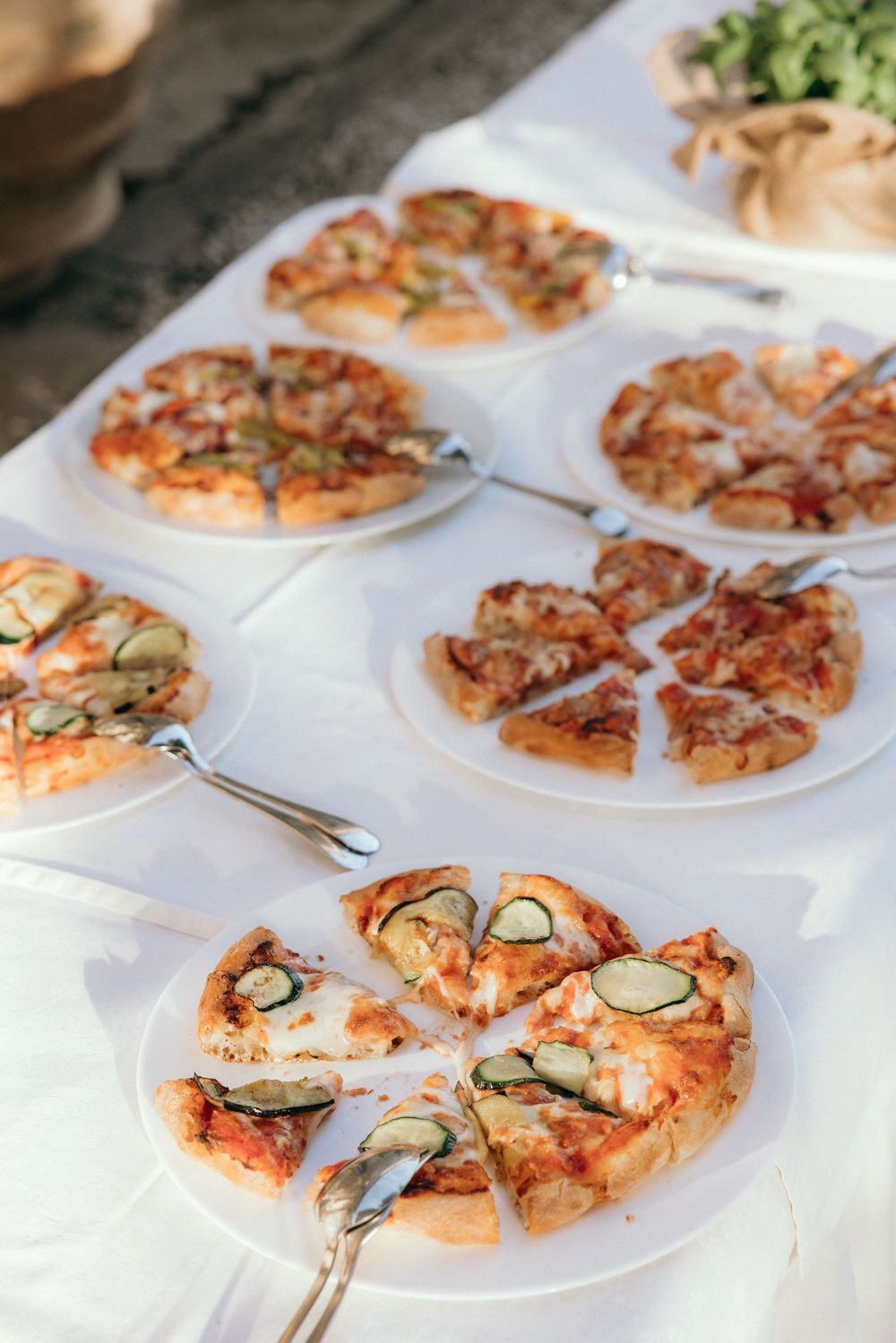 Sliced pizzas arranged on white plates with fresh herbs and toppings.