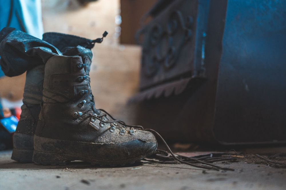 Close-up shot of hiking boots on a dark surface with dramatic lighting.