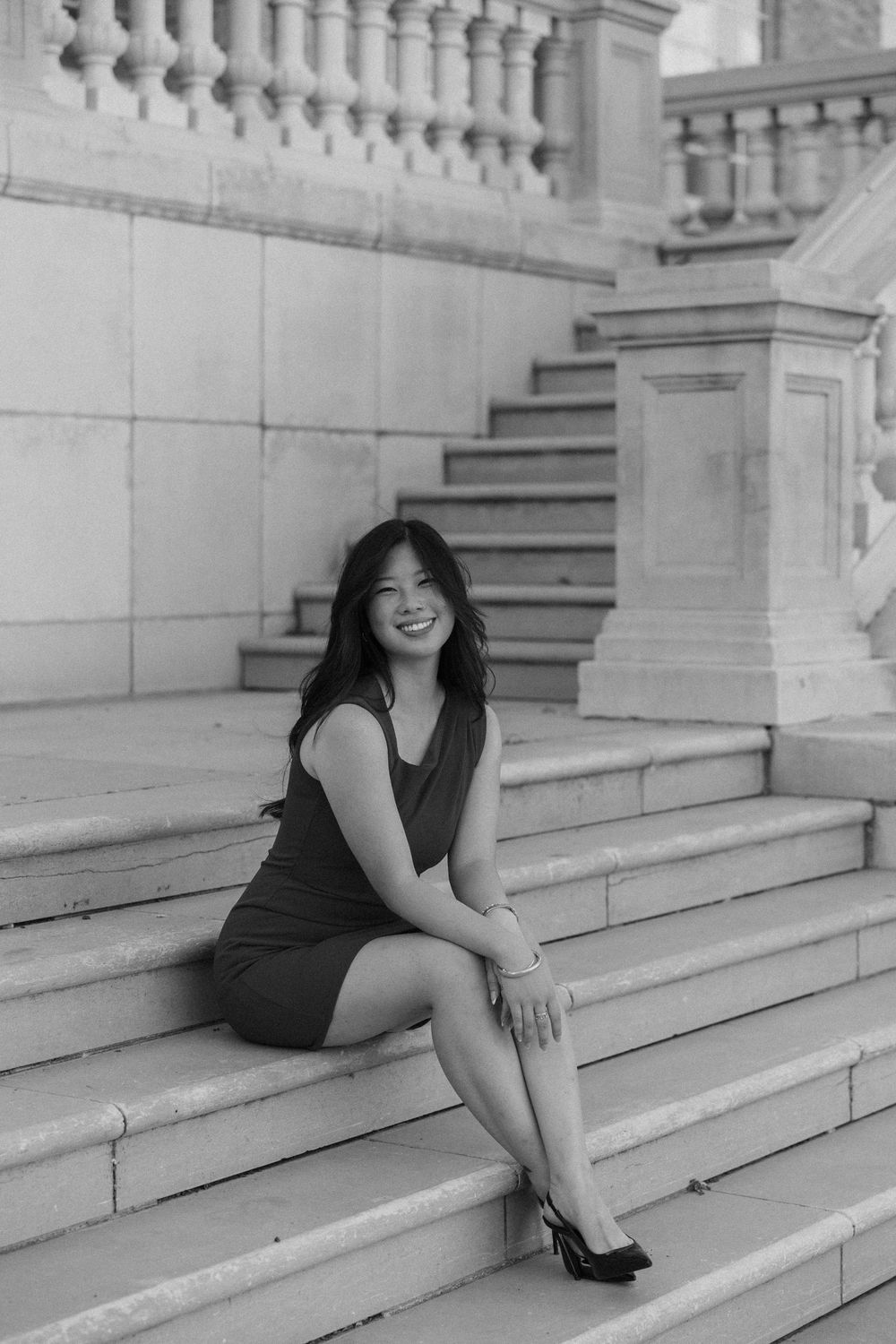 A black and white photo series showing a person in dark clothing sitting and posing on stone steps.