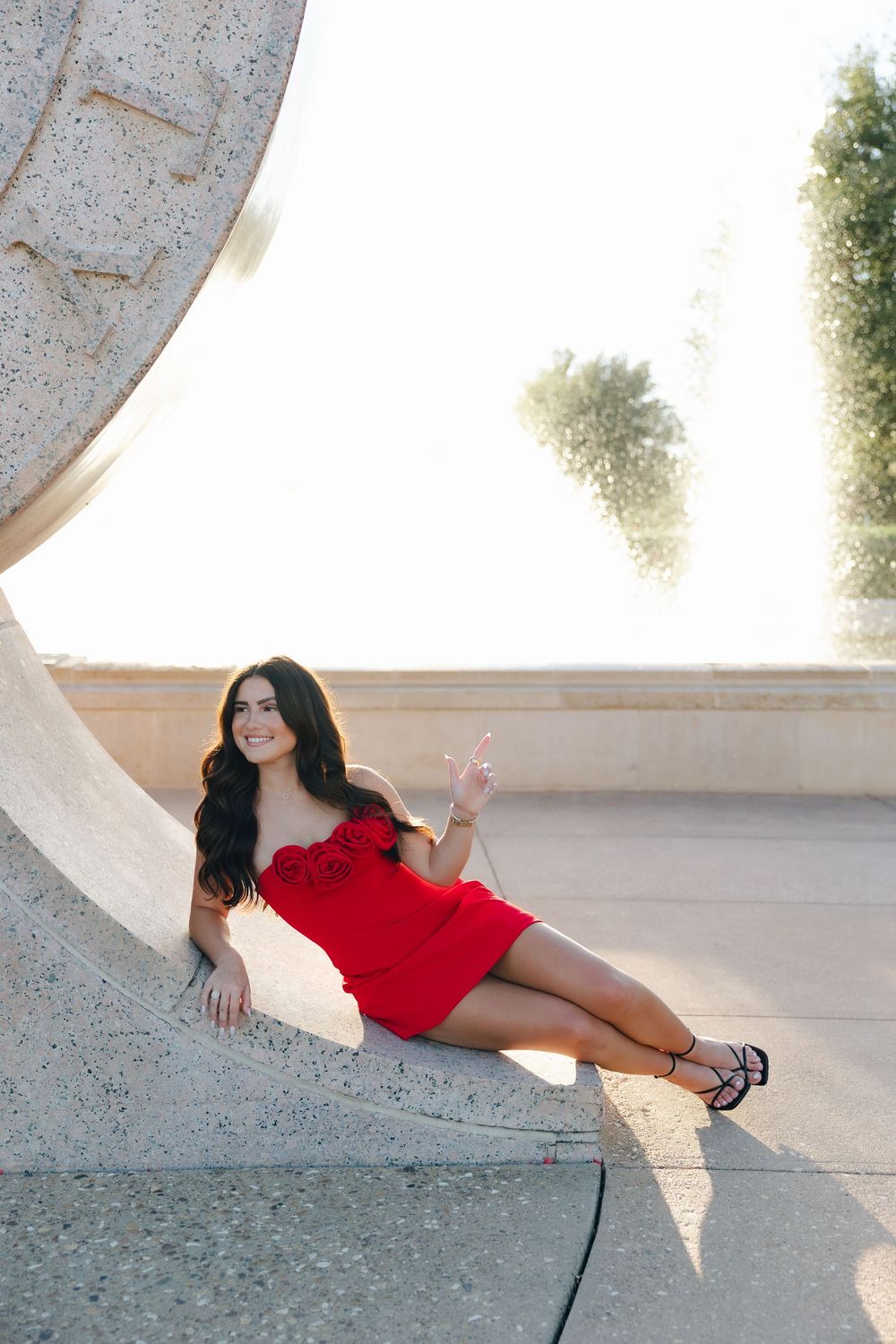 A person in a red dress poses gracefully against a light-colored architectural wall in a creative photo series.