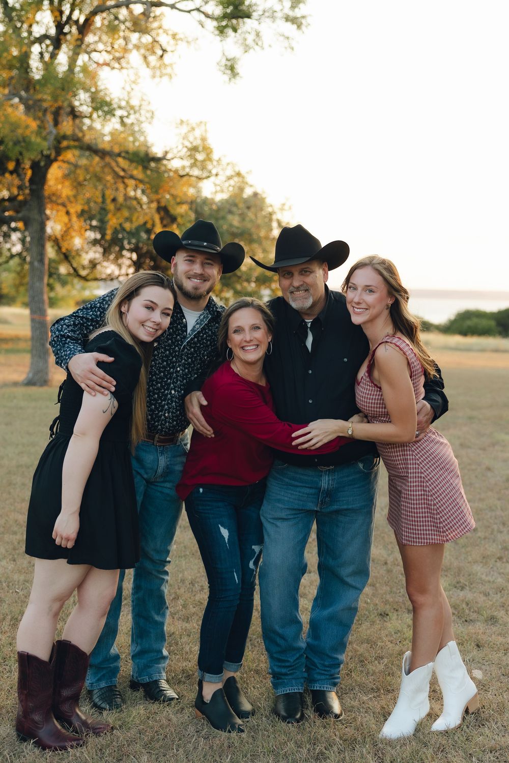 A group poses playfully together outdoors during a fall photo session in casual western attire.