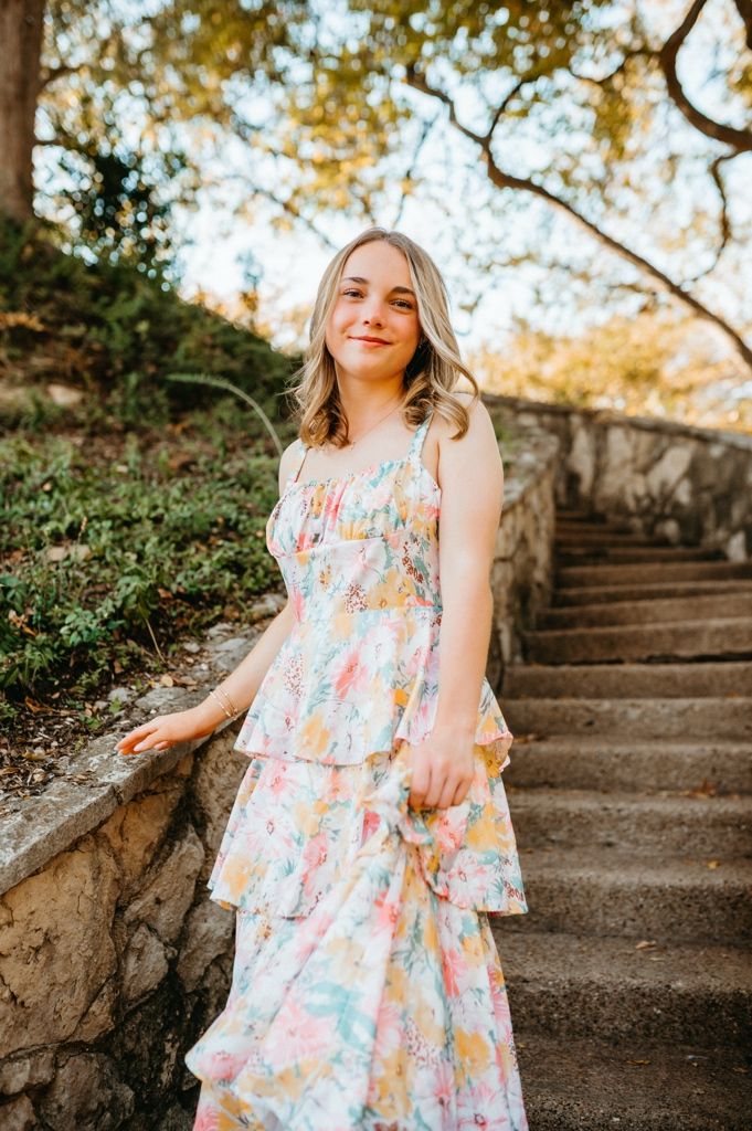 Whimsical outdoor portrait session on stone steps surrounded by lush greenery at golden hour.