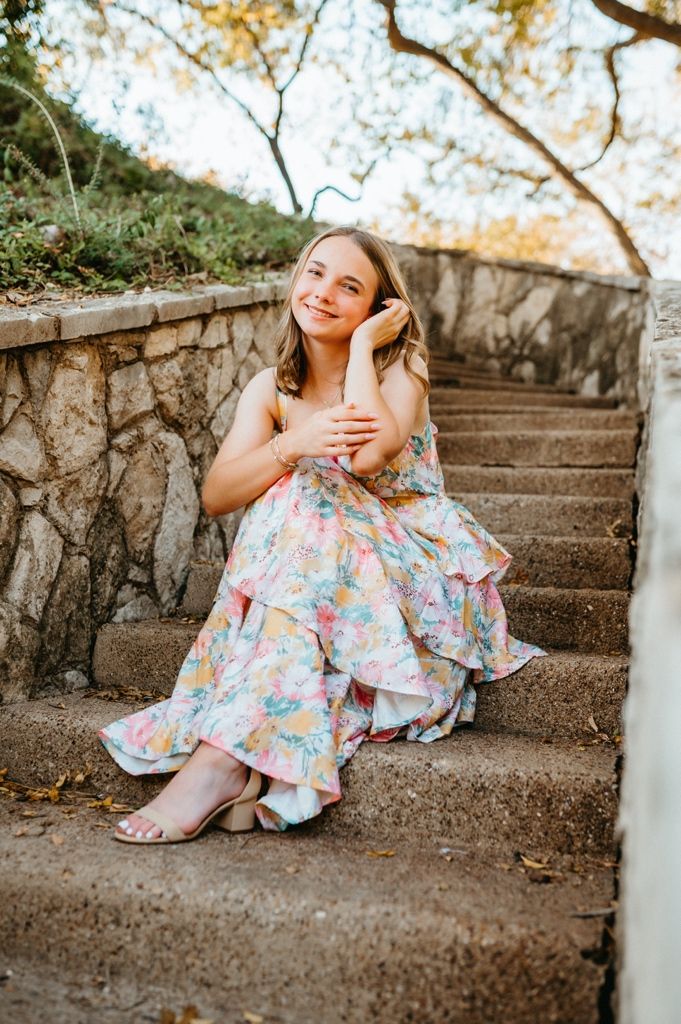 Dreamy portrait session featuring a floral dress against rustic stone steps in warm sunlight.