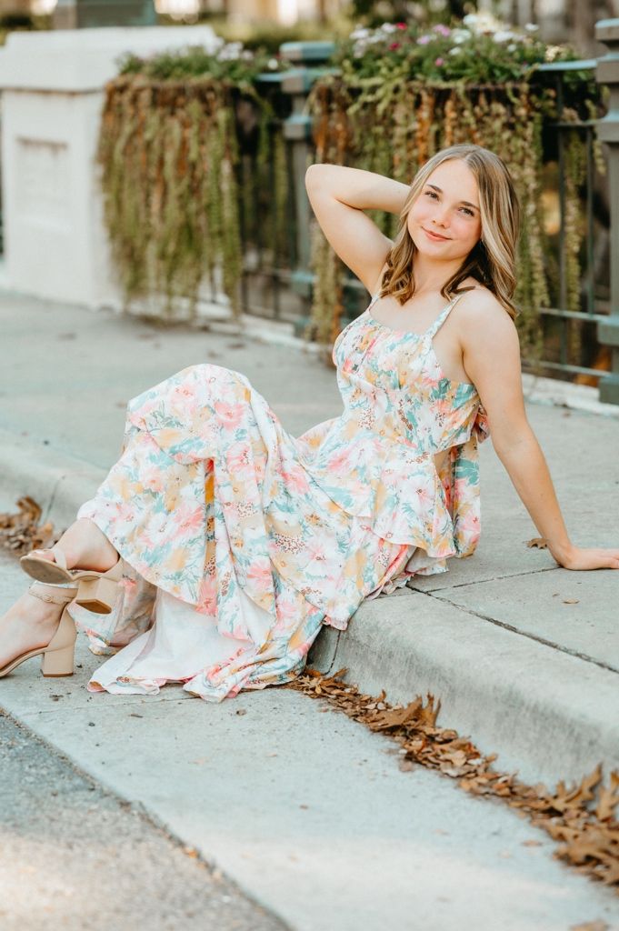 A series of photos showing a person in a floral dress reclining on a concrete curb with fallen leaves.