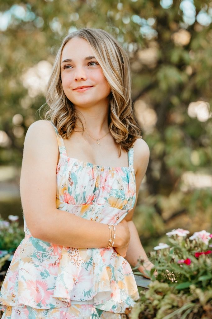 A floral sundress with ruffles is worn in a sunny garden setting with bokeh lighting effects.