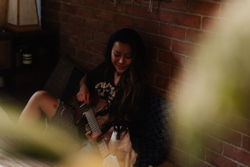 Cozy branding photo of an artist playing guitar in her living room.