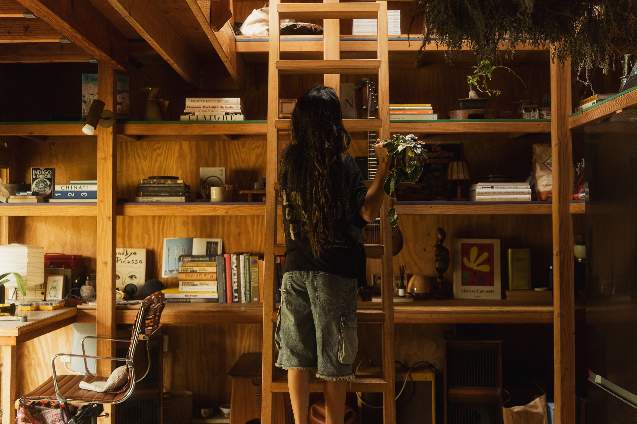 Hanna Li selecting books in her wooden home library during a personal branding session in Los Angeles.