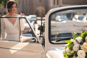 Vintage white car decorated with floral arrangements for a wedding celebration.
