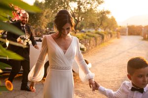 Wedding party walks along sunlit path during golden hour celebration.