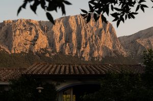 Dramatic rocky mountain cliffs glowing orange at sunset.