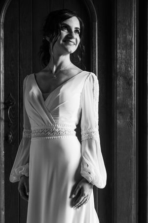 Elegant bride in vintage-inspired white wedding dress poses in dramatic lighting.