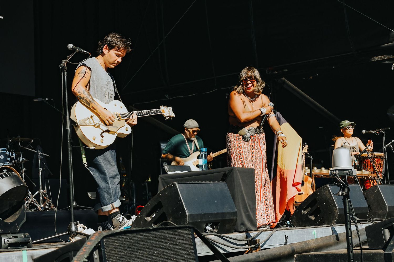 Band performing live on outdoor stage at WOMADelaide festival with guitarist and singer in colorful dress.