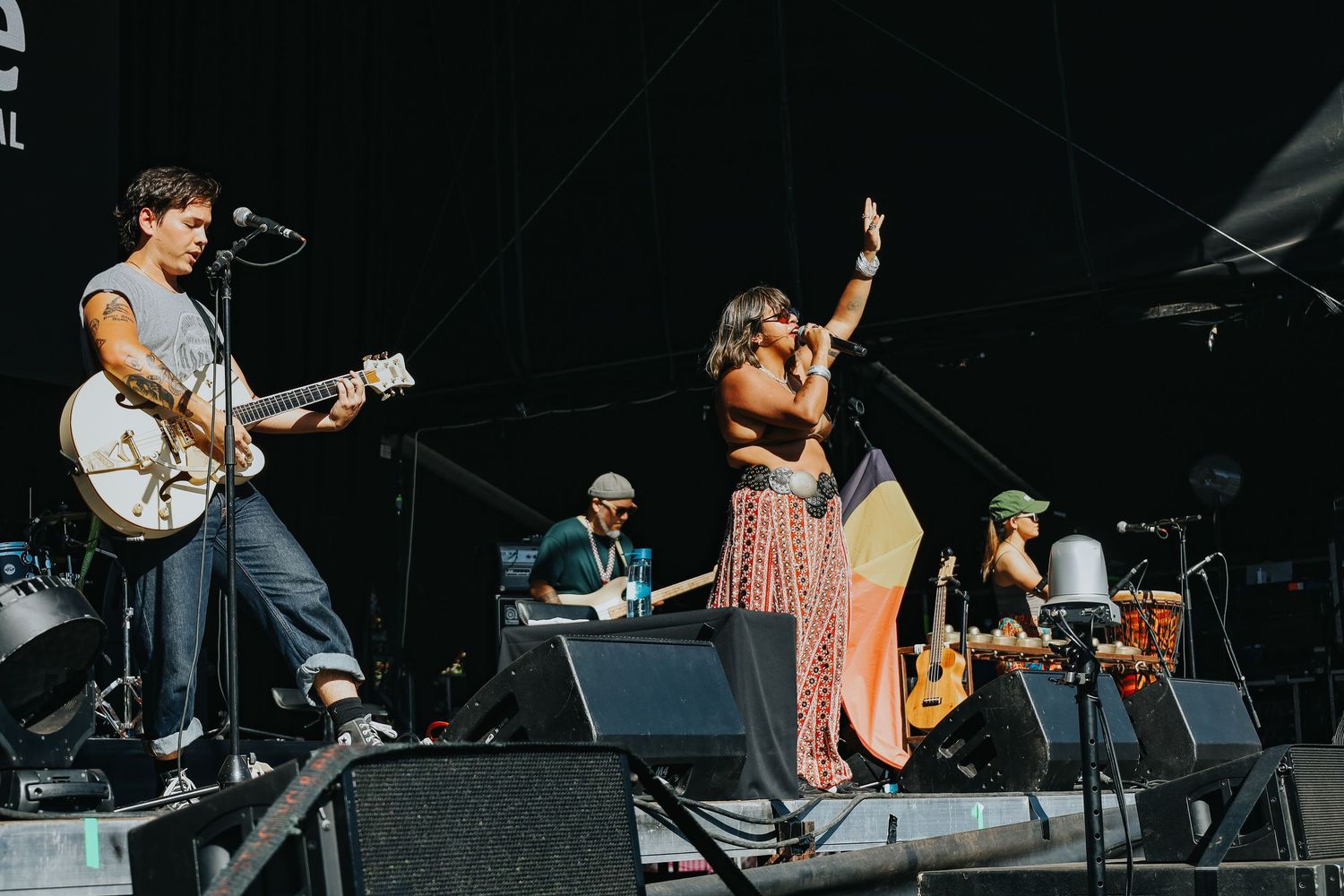 Live band performance at WOMADelaide festival with guitarist and female vocalist raising hand on outdoor stage.