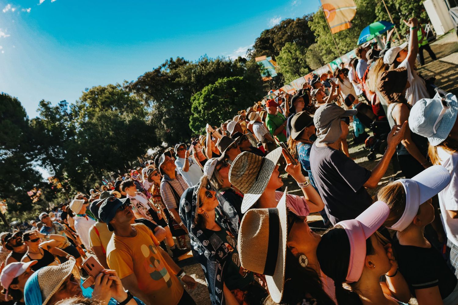 Large crowd of festival-goers wearing hats enjoying an outdoor performance at WOMADelaide festival.