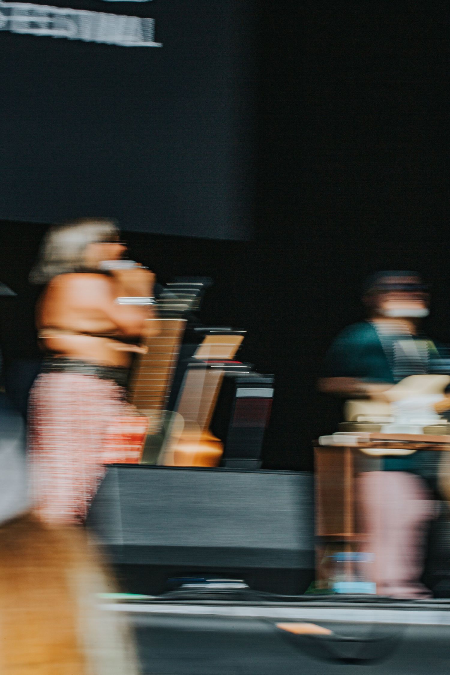 Motion blurred abstract image of performers moving on a darkened festival stage.