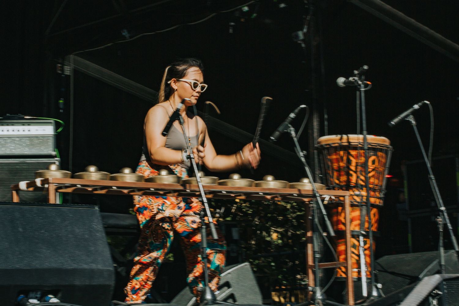 Female musician playing marimba and djembe drum on outdoor stage at WOMADelaide festival.