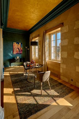 Sunlight streams through windows in an empty room with wooden floors and dark green trim creating dramatic shadows.