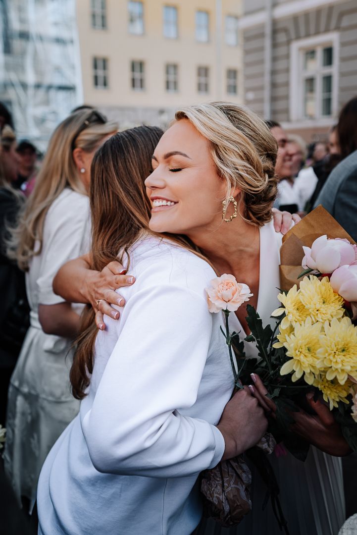 A series of four candid photos showing two people embracing while holding yellow flowers at an outdoor gathering.