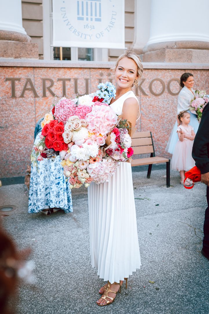 A sequence of images showing someone holding beautiful bouquets of pink and red flowers against a brick building wall.