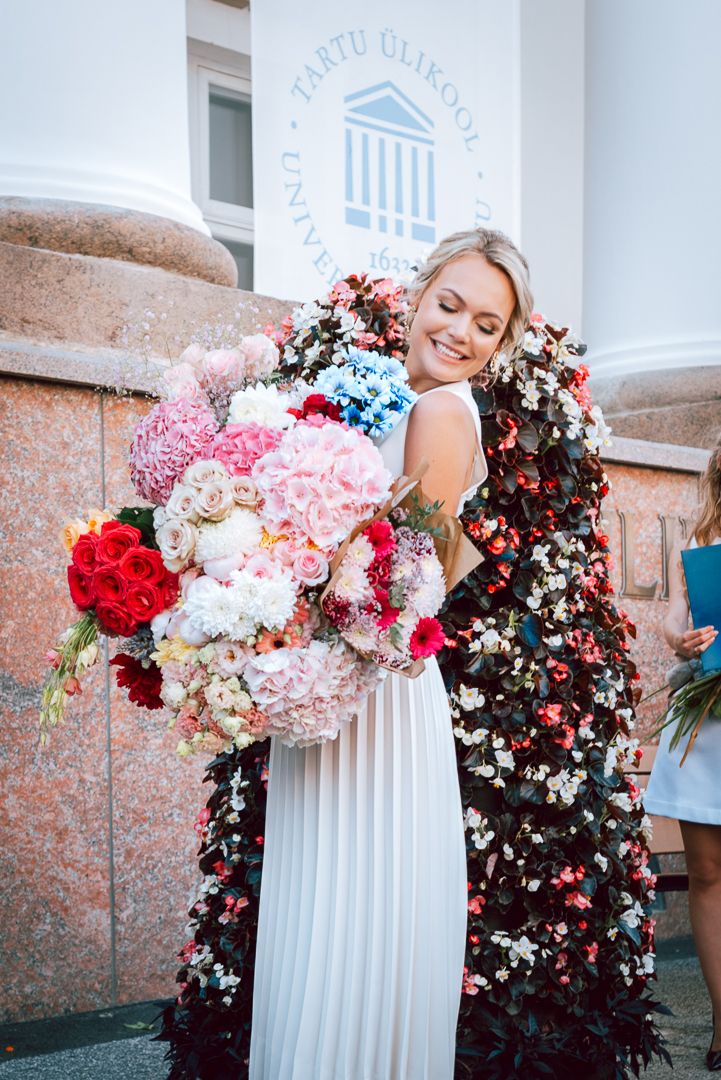 A decorative display of pink, red, and white flowers arranged against a white classical column backdrop.