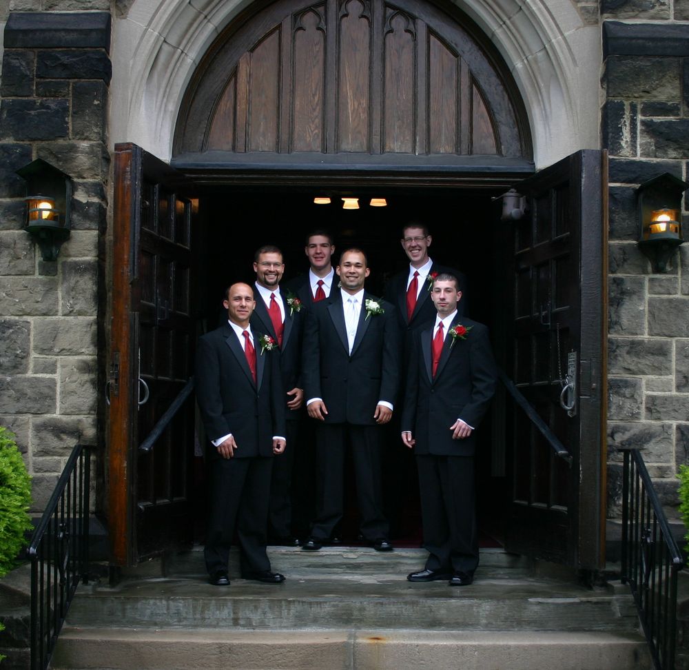 Formal group photo in front of stone church entrance with arched doorways.