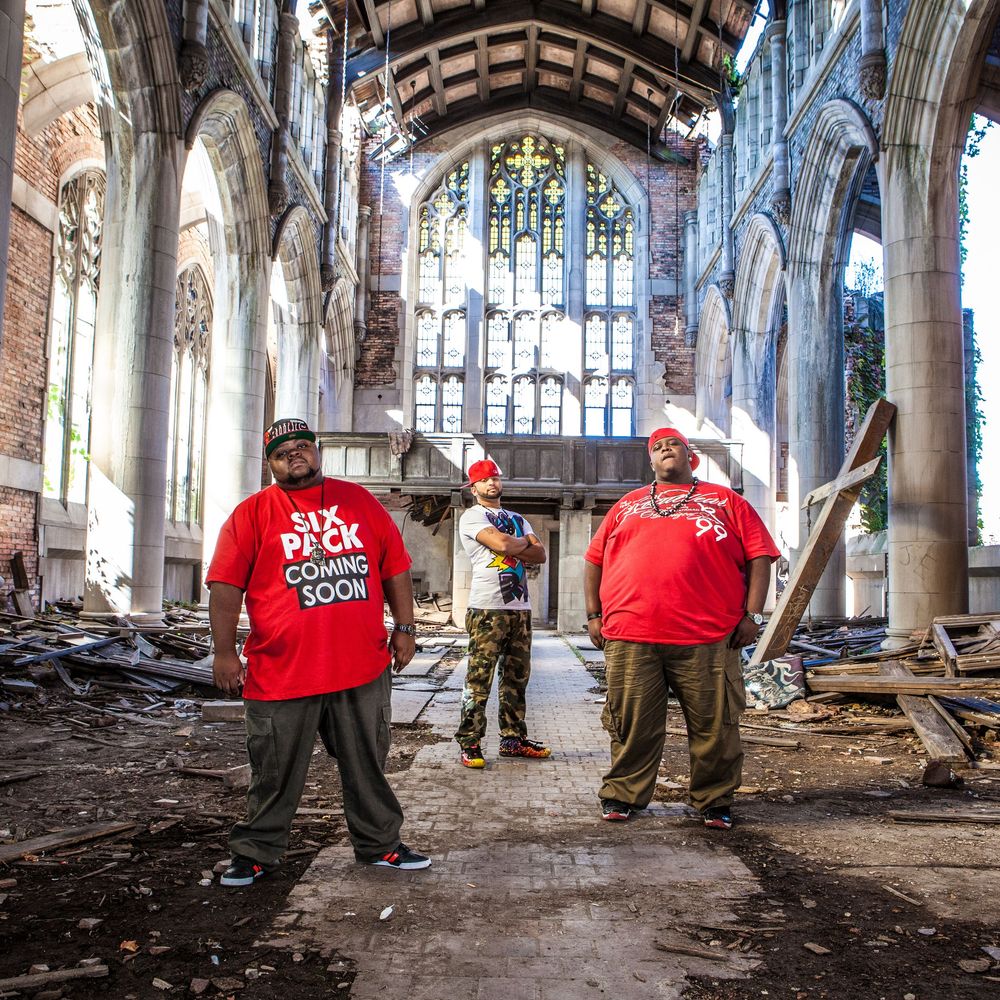 People exploring abandoned church interior with gothic architecture and debris on floor.