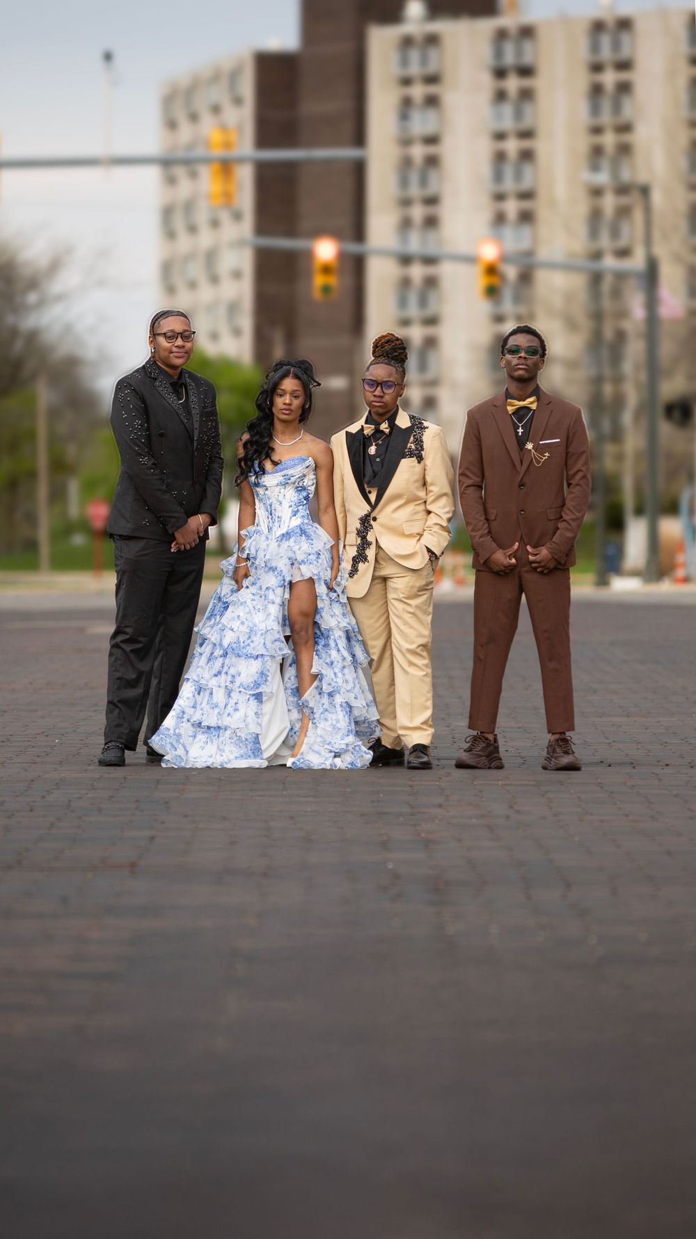 Group portrait of formally dressed people standing on brick pavement in front of urban building.