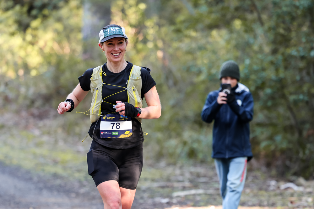 Runner wearing bib number 78 and hydration vest races on a forest trail during an ultramarathon event.