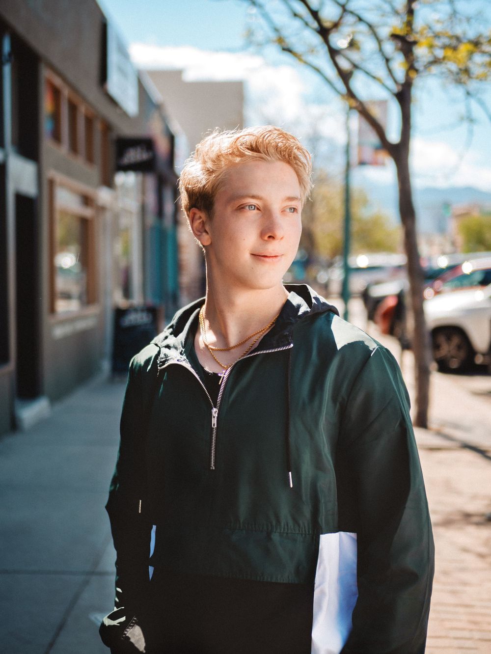 A series of photos showing a person in a black jacket walking along an urban sidewalk on a sunny autumn day.