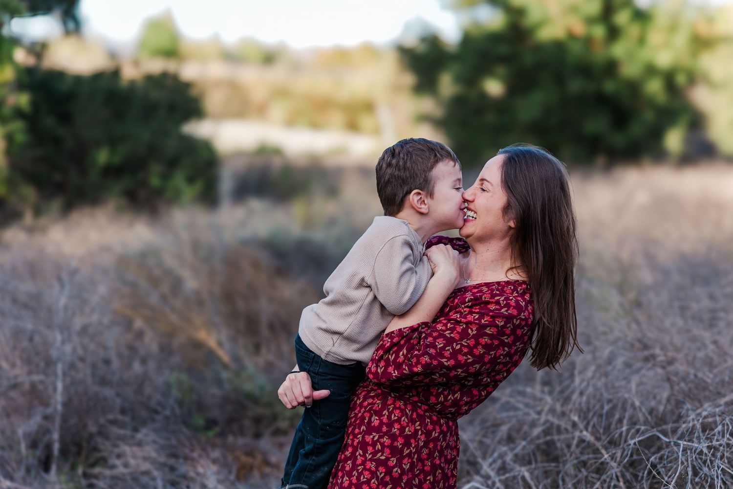 A couple in a field shares tender moments together during a romantic outdoor photoshoot at golden hour.