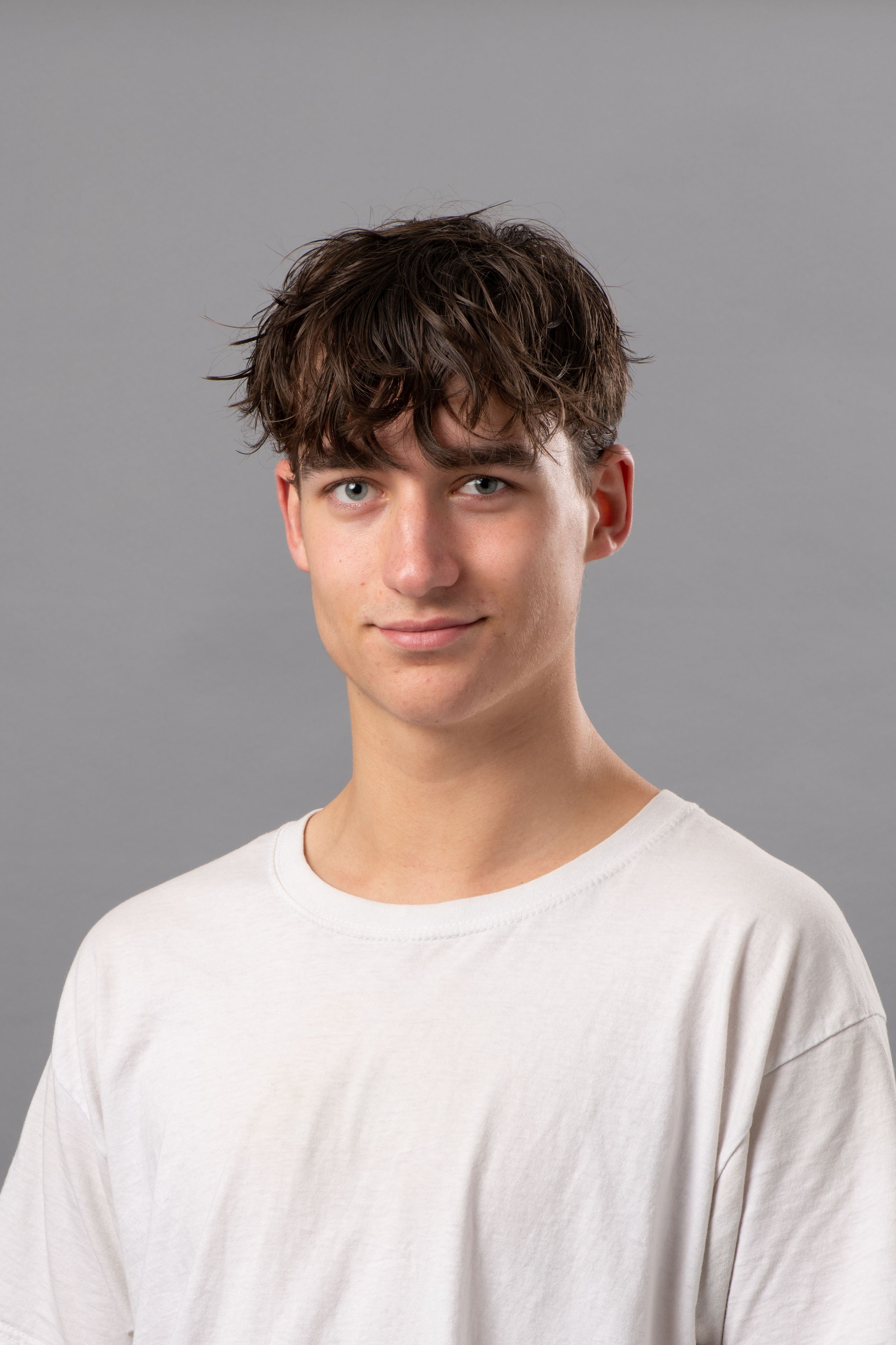 Four headshots against a gray background showing someone wearing a white t-shirt with tousled dark hair.