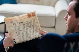 Someone reads an old manuscript or historical document with handwritten text on aged paper.